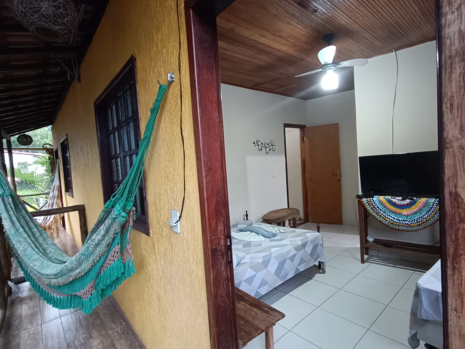 Suíte com varanda e rede, integrando o quarto com a área externa da pousada